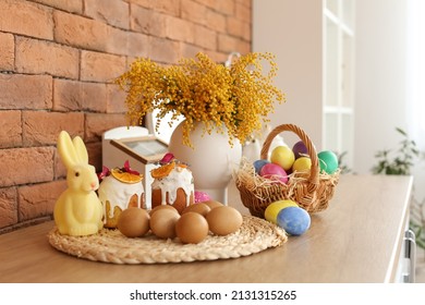 Easter Cakes, Eggs And Rabbit On Kitchen Counter Near Brick Wall