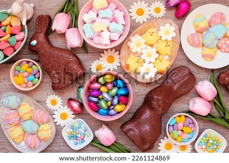 Easter candies. Top view table scene over a wood background. Chocolate bunnies, candy eggs and a variety of sweets.