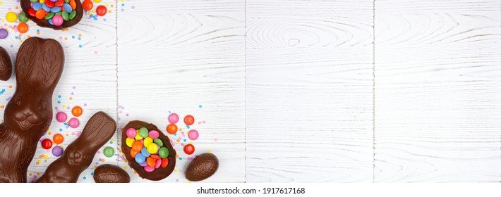 Easter Candy, Chocolate Bunnies And Eggs. Above View Corner Border Against A White Wood Banner Background. Copy Space.