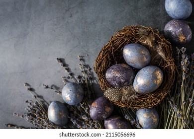 Easter card with a copy of the place for the text. Purple, blue and golden eggs with lavender on a dark background. The purple hue trend of 2022 is very relevant. Natural dye karkade tea. Top view.