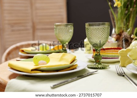 Easter celebration. Festive table setting with elegant dishware and painted eggs, closeup
