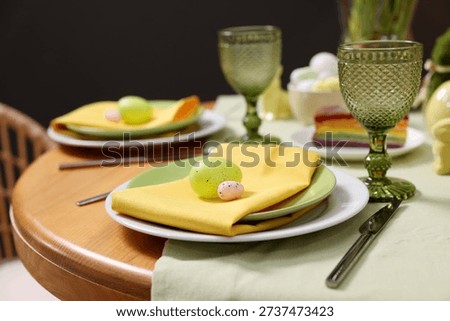 Easter celebration. Festive table setting with elegant dishware and painted eggs, closeup