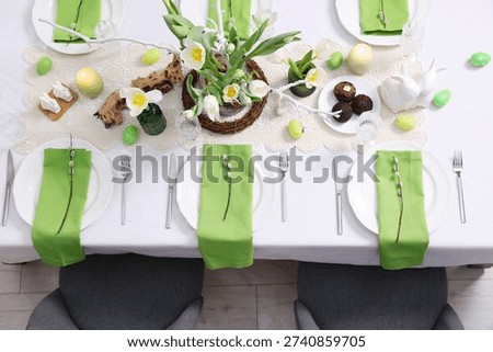 Easter celebration. Festive table setting with elegant dishware and flowers, top view