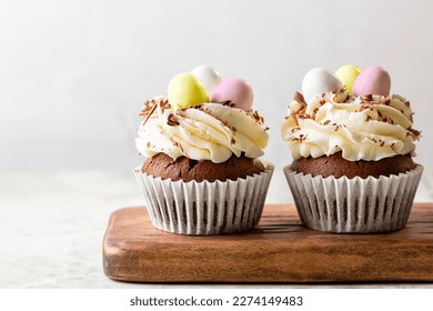 Easter chocolate cupcakes with cream cheese, sweet candy eggs and nest. Holiday homemade dessert. Close-up. - Powered by Shutterstock