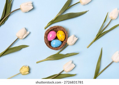 Easter colored painted eggs in bird nest with white tulips on gray background with space for text and greetings. Easter and spring concept. Spring background