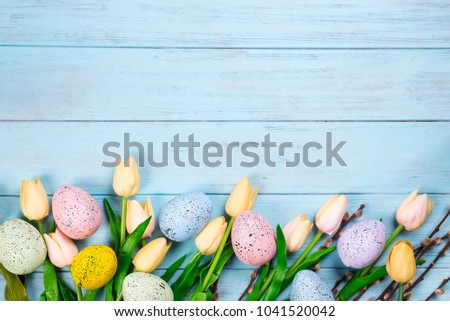 Easter colorful eggs with tulips on wood background as frame