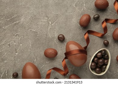 Easter composition with chocolate eggs and brown ribbon on grey background. Top view