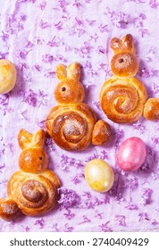 Easter composition made of sweet buns in the shape of a rabbit, eggs and lilacs.