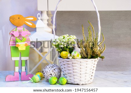 Easter composition on a marble table surface from a white wicker basket with spring flowers, clay chicken, colored eggs, lantern
, wicker ball, rabbit. Decoration home interior for easter
