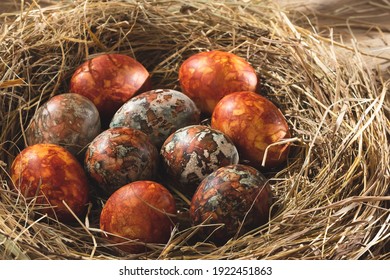 Easter composition - orange marble Easter eggs painted with natural dyes in a nest of hay