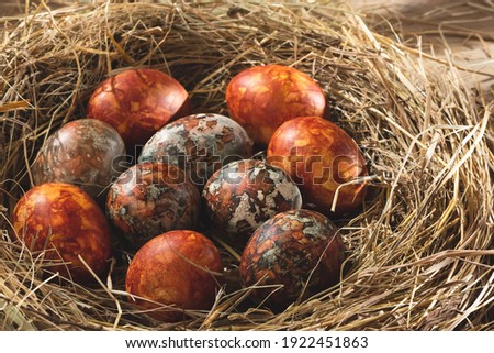 Easter composition - orange marble Easter eggs painted with natural dyes in a nest of hay