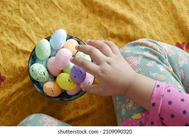 Easter Concept With Child Hand Pick Colorful Egg On Pink Background.