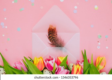 Easter Concept, Golden Star Decorations, Vibrant Confetti And Open Matte Transparent Envelope With Feathers, Multicolored Tulips And Quail Eggs On Pink Background.