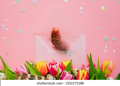 Easter Concept, Golden Star Decorations, Vibrant Confetti And Open Matte Transparent Envelope With Feathers, Multicolored Tulips And Quail Eggs On Pink Background.