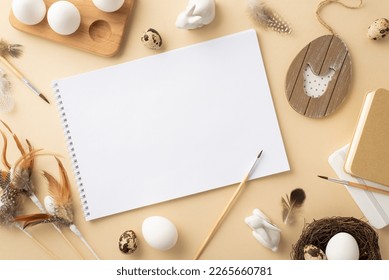 Easter concept. Top view photo of sketchbook paintbrushes quail eggs wooden egg holder rustic decor nest ceramic bunnies and quail feathers on isolated beige background with blank space - Powered by Shutterstock