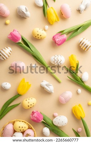 Easter concept. Top view vertical photo of colorful easter eggs in bowl ceramic easter bunnies yellow and pink tulips on isolated light beige background