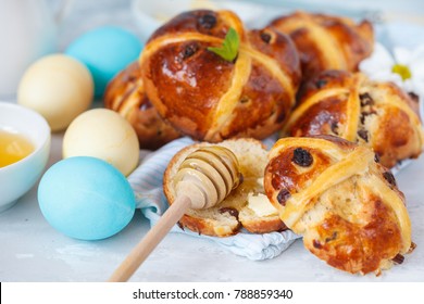 Easter cross buns with honey and butter, painted eggs. Light background, copy space