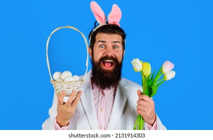 Easter Day. Rabbit Man In Bunny Ears With Flower. Bearded Male In Suit Holds Basket With Eggs.