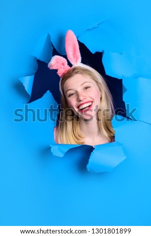 Easter Day. Through paper. Happy easter! Woman with bunny ears. Smiling woman looking through paper. Egg hunt. Easter. Bunny. Easter hunt. Bunny ears. Breaking paper. Sale. Discount.