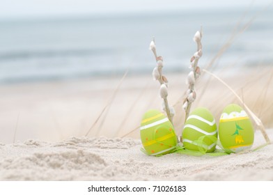 Easter Decorated Eggs And Catkin On Sand. Beach And Ocean In The Background