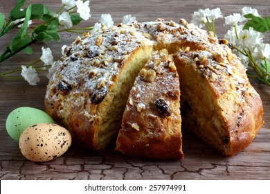  Easter decoration - sweet braided homemade sliced bread with easter eggs and florets with leaves decorated on wooden desk - table - easter time