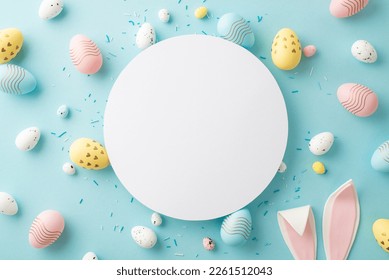 Easter decorations concept. Top view photo of white circle colorful easter eggs bunny ears and sprinkles on isolated light blue background with copyspace