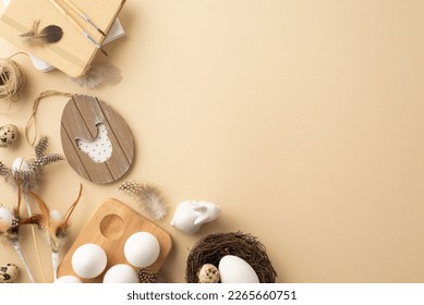 Easter decorations concept. Top view photo of easter eggs in wooden holder quail nest ceramic rabbit sketchbook paintbrushes and feathers on isolated pastel beige background with copyspace - Powered by Shutterstock