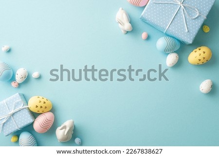 Easter decorations concept. Top view photo of blue gift boxes colorful easter eggs and ceramic bunnies on isolated pastel blue background with blank space