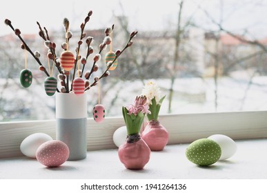 Easter decorations on windowsill, panoramic image. Wooden painted eggs on pussy willow. Hyacinth flowers with bulbs in pink wax. Window, view over town. Romantic indoor setup. Happy Easter