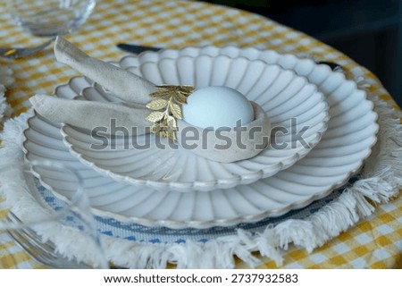 Easter dinner. Beautifully set table featuring blue Easter egg nestled in decorative napkin resembling bunny ears. 