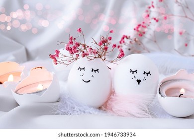 Easter DIY do it yourself. Minimal easter concept. Easter eggs with painted smiley faces and bird feather on pastel background. Married. Valentines day Wedding couple eggs. Easter holiday concept 
