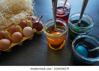   Easter Egg Dying Process. Transparent glass cups with colored water and Colored eggs 