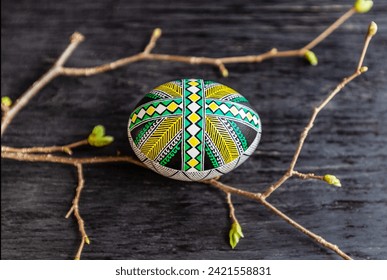 Easter egg with green geometric ornament on a dark wooden background and spring twigs. - Powered by Shutterstock