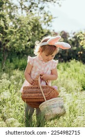 Easter egg hunt. Girl child Wearing Bunny Ears Running To Pick Up Egg In Garden. Easter tradition. Baby with basket full of colorful eggs. - Shutterstock ID 2254982715