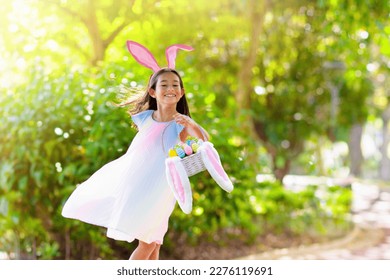 Easter egg hunt. Little girl with bunny ears celebrating Easter. Kids celebrate spring holiday. Children search chocolate eggs and candy. Rabbit costume. Christian holidays with child. - Powered by Shutterstock