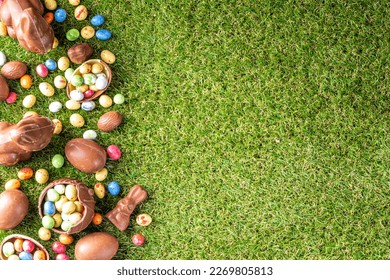 Easter egg hunting background. Various candy and chocolate Easter eggs, bunny and rabbits with basket for eggs on green grass park or garden background - Shutterstock ID 2269805813