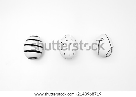 Easter egg with minimalistic black pattern. Ornament of stripes, lines and dots. Chicken eggs on white background. Festive card for religious holiday Happy Easter. Preparing for celebration. Farm food