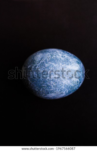 Easter egg painted in the form of a planet in\
space in blue on a black background. Marble dyed for Easter painted\
in hibiscus