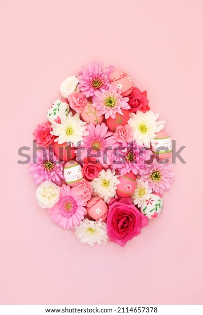 \
Easter egg shape concept with decorated eggs and\
flowers on pastel pink background. Spring and Easter abstract\
design. Top view, copy\
space.