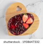 Easter egg stuffed with strawberry jam on a wooden support with a white marble background