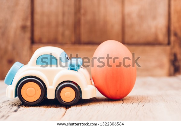 Easter egg and toy car on wooden background,
happy easter day concept