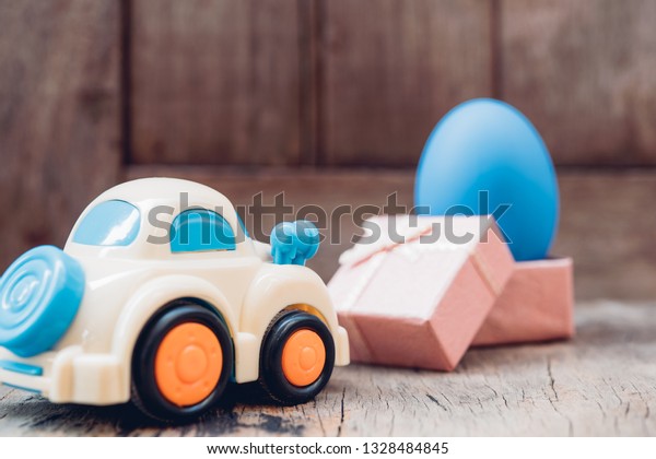 Easter egg and toy car on wooden background,\
happy easter day concept
