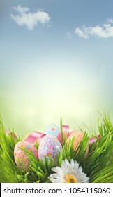 Easter Eggs background. Beautiful colorful eggs in spring grass meadow over blue sky with sun border design. Vertical screen backdrop, wallpaper art design with copy space for your text. Easter scene