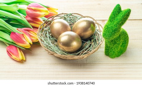 Easter eggs basket. Golden egg in basket with spring tulips, white feathers on wooden background in Happy Easter decoration. Traditional decoration in sun light - Powered by Shutterstock