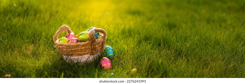 Easter eggs in a basket in green grass. Spring season traditional egg hunt colorful decorated eggs in a wicker basket.  - Powered by Shutterstock