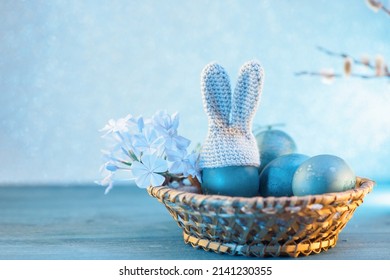 Easter eggs in a basket on a blue bokeh background. Crocheted hat with bunny ears . Easter Creative Greeting card