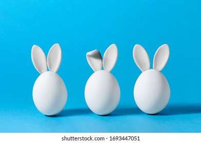 Easter Eggs with Bunny Ears on Blue Background. Creative Greeting Card. Minimalism Concept. Copy Space - Powered by Shutterstock