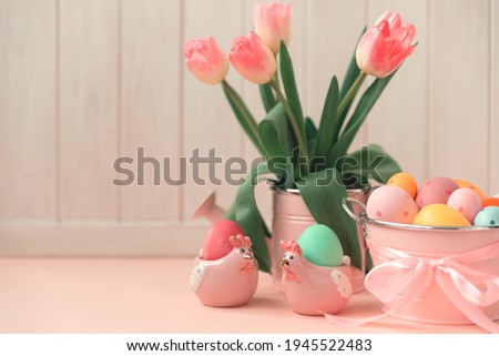 Easter eggs, ceramic hen and wase with tulips on pink wooden table. Easter celebration concept. Soft focus