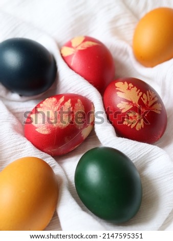 Easter eggs decorated by hand with fresh natural leaves from the garden, lovely texture, red dye with natural motifs, group of eggs on white fabric