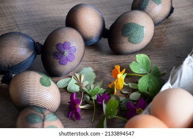 Easter eggs decorated with leaves and flowers, prepared for natural dyeing with onion skins